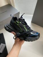 Sneaker premium nero e verde con dettagli futuristici e brand di lusso.
