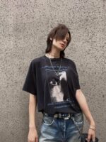 Moda streetwear: t-shirt oversize con gatto, jeans distressed e accessori metallici urbani.