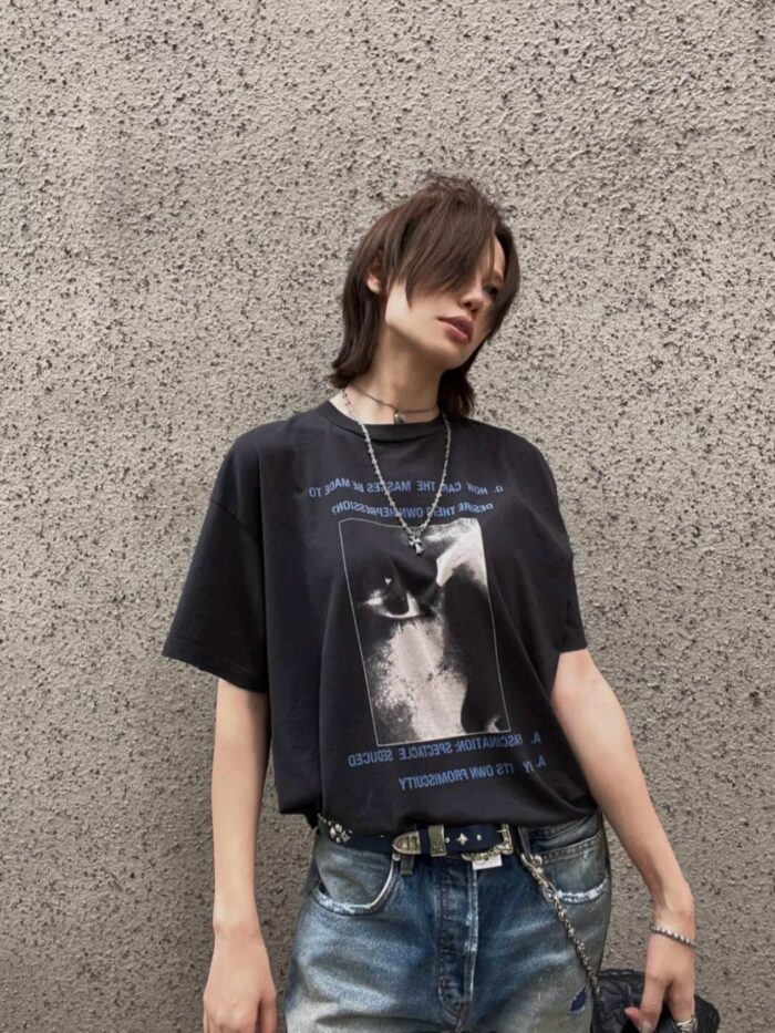 Moda streetwear: t-shirt oversize con gatto, jeans distressed e accessori metallici urbani.