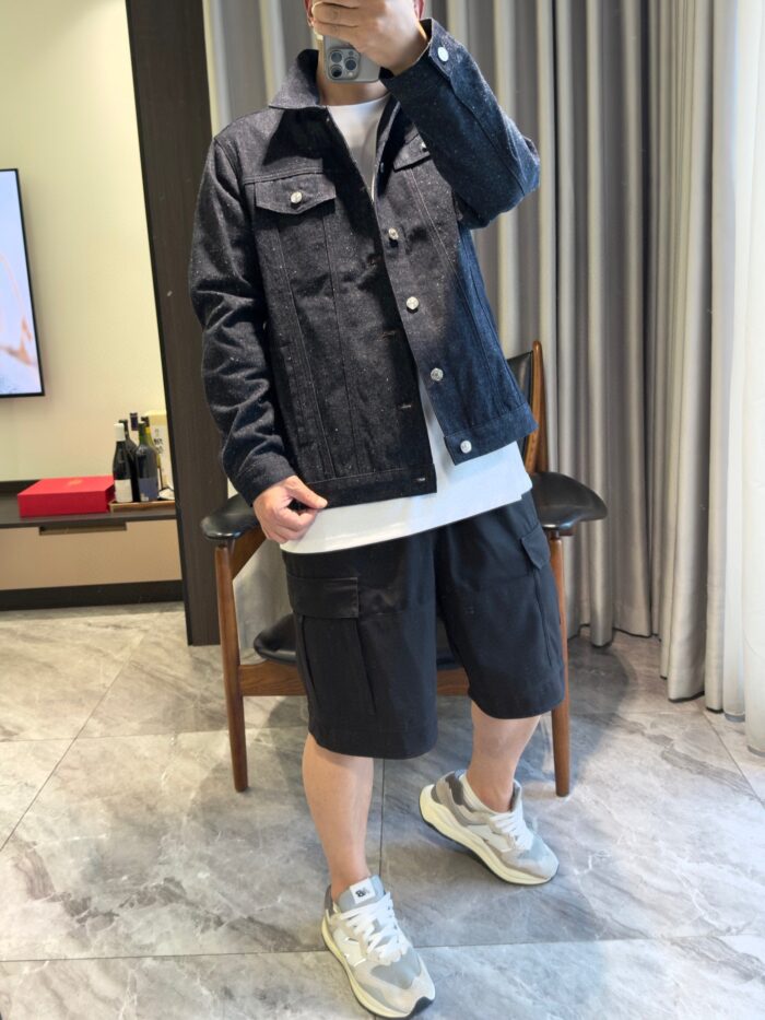 Giovane con giacca denim, t-shirt bianco e sneakers trendy in ambientazione moderna e rilassata.