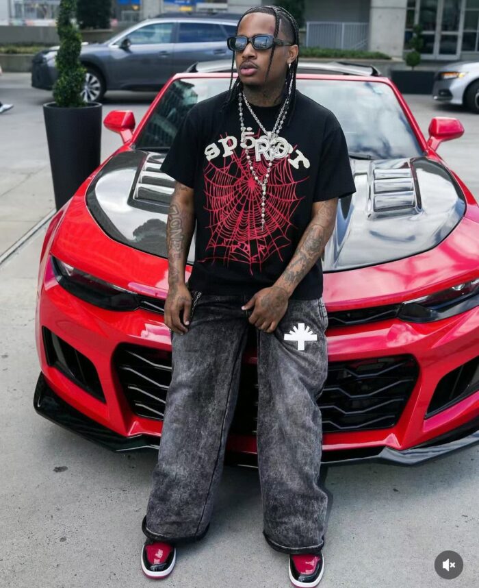 Uomo streetwear accanto a Chevrolet Camaro rossa, stile urbano, moda, auto sportiva e energia.