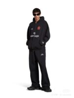 Stile streetwear total black con giacca oversize, pantaloni comodi e sneakers chunky.