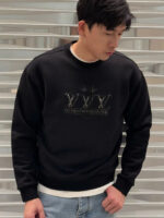 Giovane in streetwear con felpa nera con grafica e corona, stile urbano e casual.