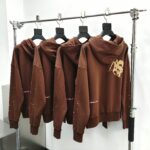 Felpe marroni minimaliste con grafica sljn, stile urbano e casual su esposizione moderna.