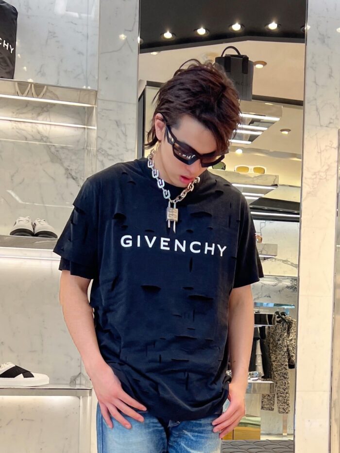 Giovane in stile streetwear di lusso con Givenchy e accessori moderni in ambiente raffinato.