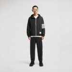 Giovane uomo alla moda con outfit sportivo nero, occhiali oversize e stile moderno.