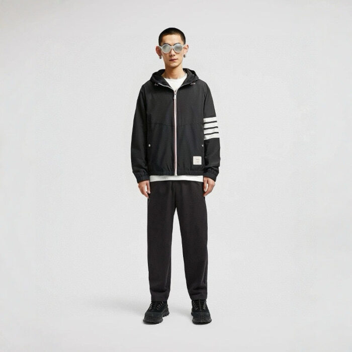 Giovane uomo alla moda con outfit sportivo nero, occhiali oversize e stile moderno.