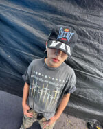Stilista streetwear urban con T-shirt oversize, cappellino SAINT WAR e pantaloni camouflage