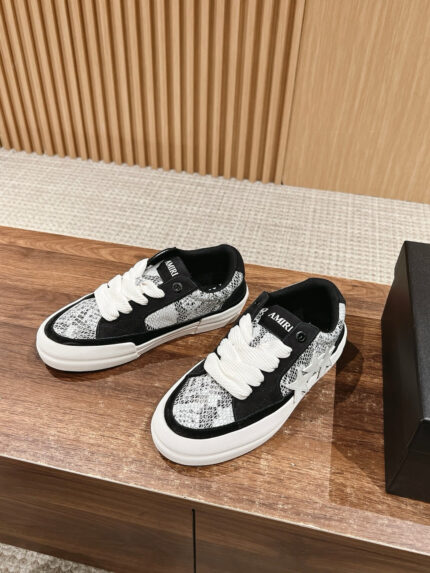 Sneakers nere e bianche con texture animalier, stile streetwear e design audace su superficie di legno.