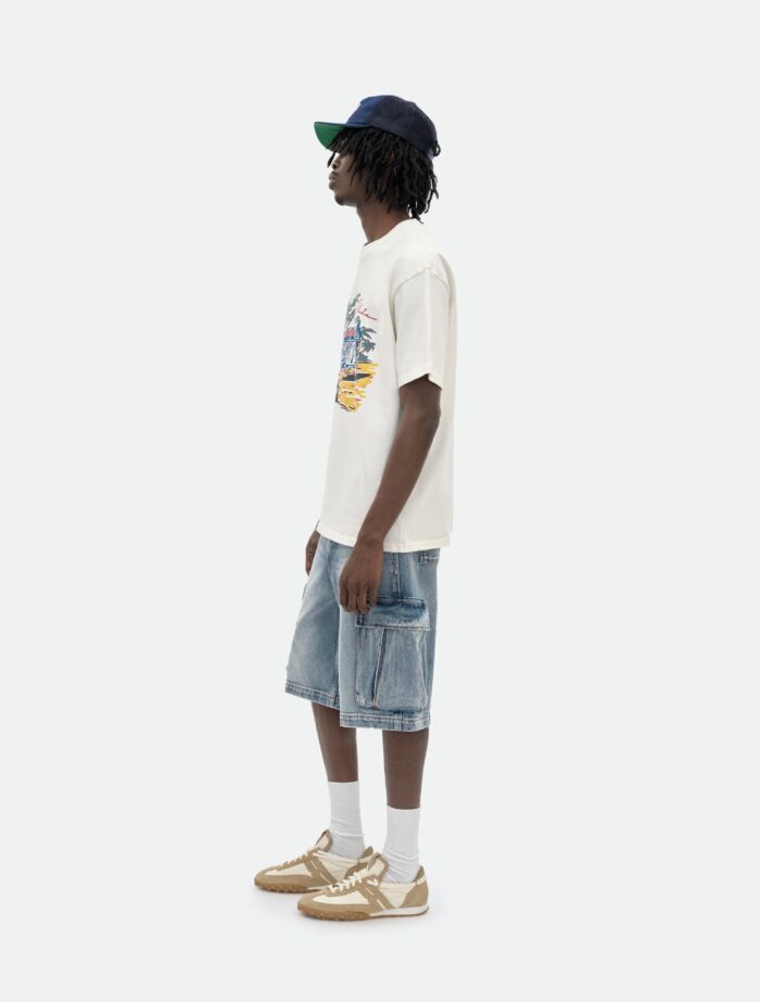 Ragazzo giovane in streetwear estivo con t-shirt, shorts denim, sneakers e cappellino backward.