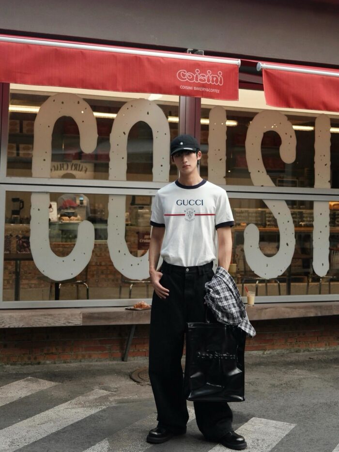 Giovane con Gucci, street style, davanti a negozio colorato in zona urbana vivace.