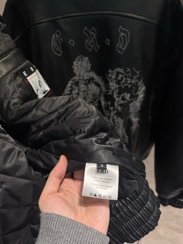Giacca nera moderna con design artistico, dettagli trapuntati e etichetta di cura interna.