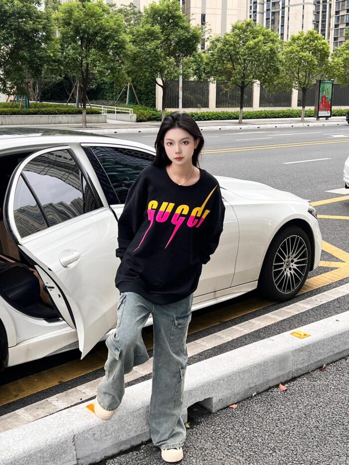 Donna giovane elegantemente casual accanto a auto di lusso in una strada urbana moderna.