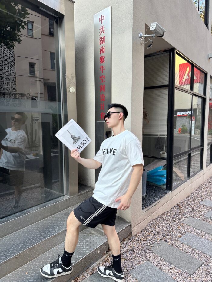 Giovane uomo con documenti davanti a edificio moderno, stile giovane e urbano.