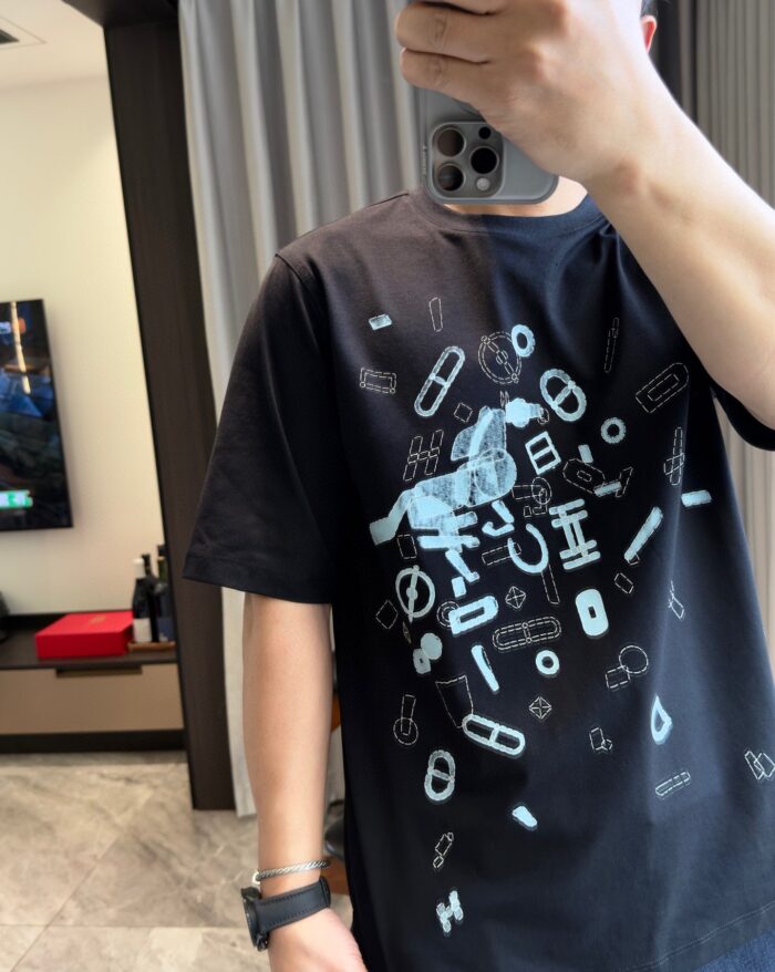 Giovane con T-shirt grafica astratta, selfie in ambiente moderno e luminoso.