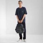Giovane uomo in stile casual urbano con zaino moderno e sneakers bianche.