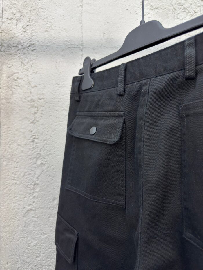 Pantaloni neri utilitari con tasca patch, cinturino e stile moderno, ideali per uso pratico e versatile.