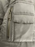 Giacchetto invernale grigio con zip diagonale e tasca frontale elegante.