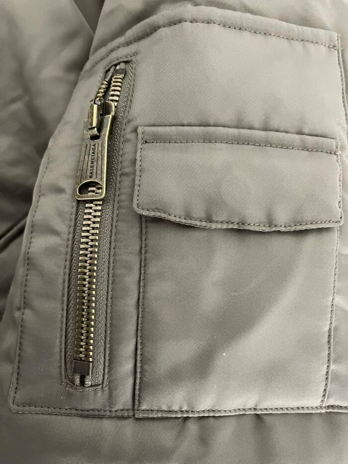 Giacchetto invernale grigio con zip diagonale e tasca frontale elegante.