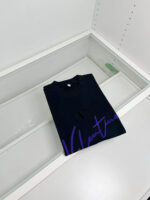 Maglietta nera Valentino con scritta viola, display minimalista e elegante per negozio di moda.