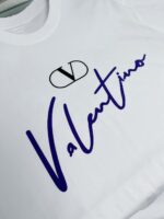 T-shirt bianca Valentino logo blu, stile elegante e moderno, perfetta per un look di lusso.