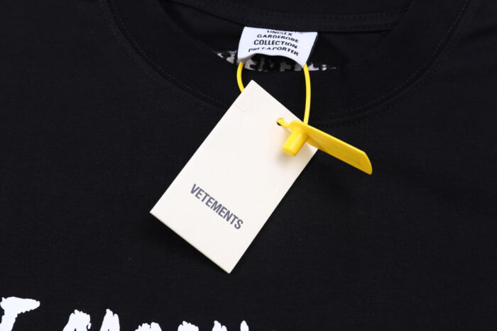 T-shirt nera Vetements con tag bianco e fermo giallo attraente e stile urbano moderno.