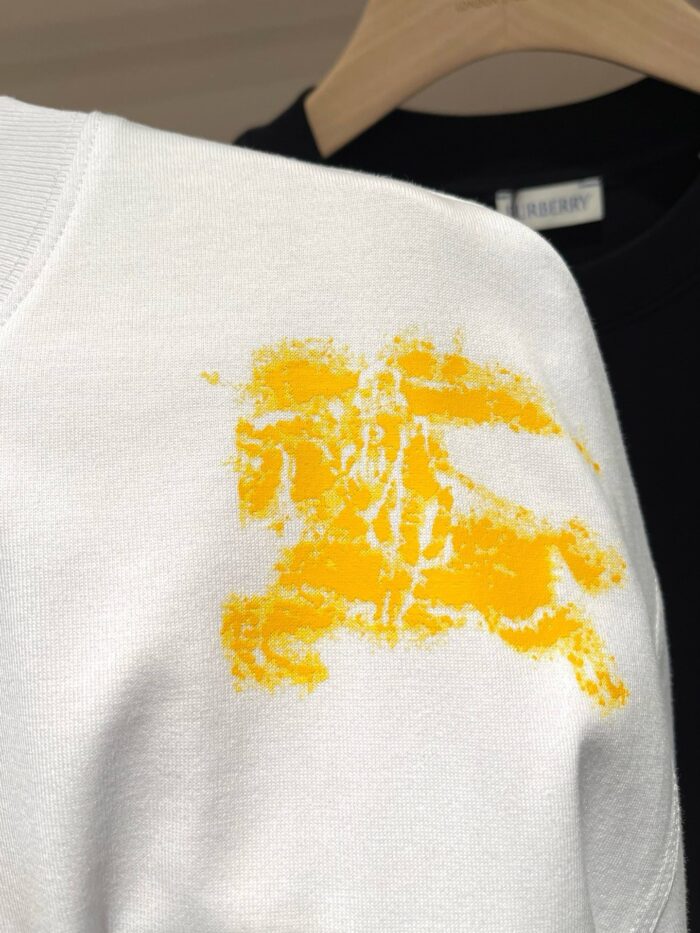 Maglietta bianca con design astratto giallo, stile moderno e fashion, sfondo nero sfocato.