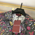 Camicia Gucci con motivi floreali e farfalle colorate, elegante e di alta moda.