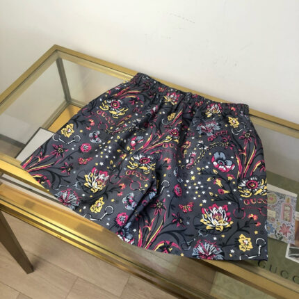 Shorts estivi colorati con motivo floreale su tavolo di vetro, stile moderno e vivace.