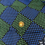 Tessuto con motivo geometrico a chevron blu e verde, boton giallo centrale vivace.