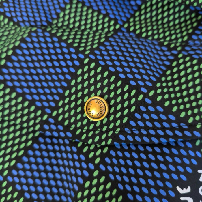 Tessuto con motivo geometrico a chevron blu e verde, boton giallo centrale vivace.