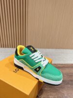Sneaker verde brillante con dettagli neri e fodera gialla su scatola di lusso arancione.