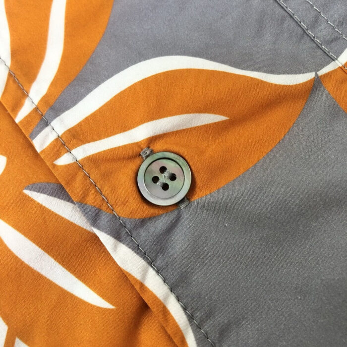Camicia estiva con motivo tropicale, bottoni neri e colori vivaci, perfetta per l’estate.