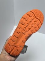 Suola arancione per scarpe sportive, trame antiscivolo e supporto ergonomico per attività allaperto.