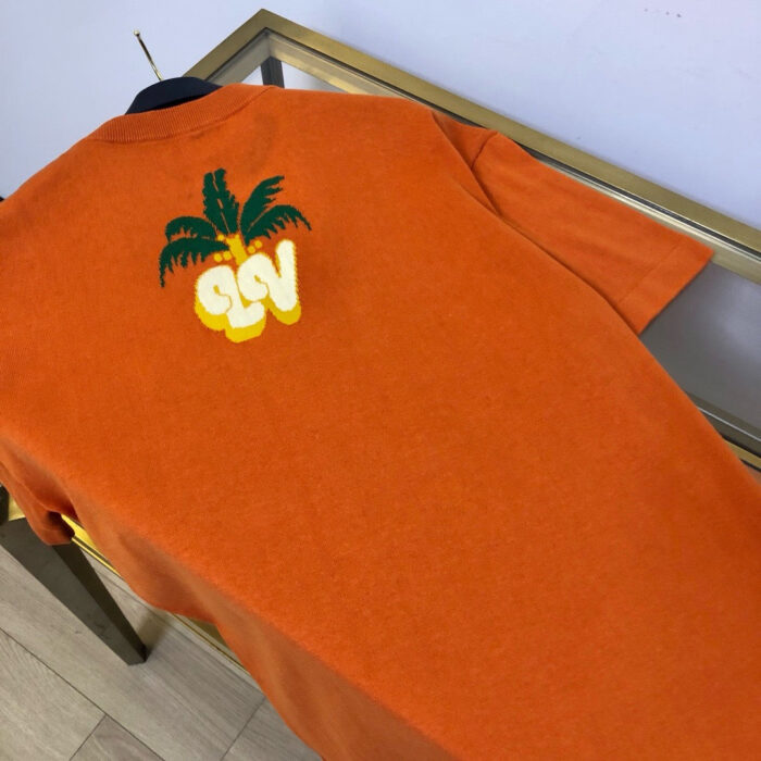 Maglietta arancione con grafica palme e logo SLY, stile estivo e casuale.