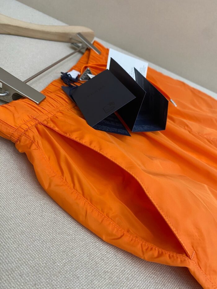 Pantaloncini arancioni estivi leggeri con elastico, dettagli ruffle e tag moderni in negozio.