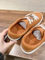 Sneakers arancioni moderne con lacci bianchi, stile casual e design confortevole.