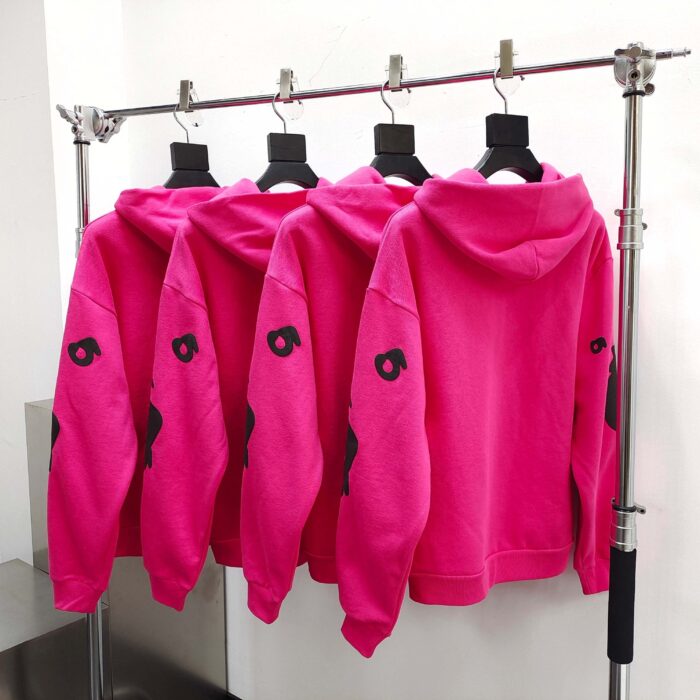 Giacche hoodie rosa fluo con grafica nera in esposizione moderna e minimalista.