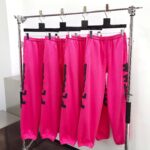 Pantaloni jogger rosa con grafica nera, stile streetwear, su supporto moderno in vetrina moda urbana.