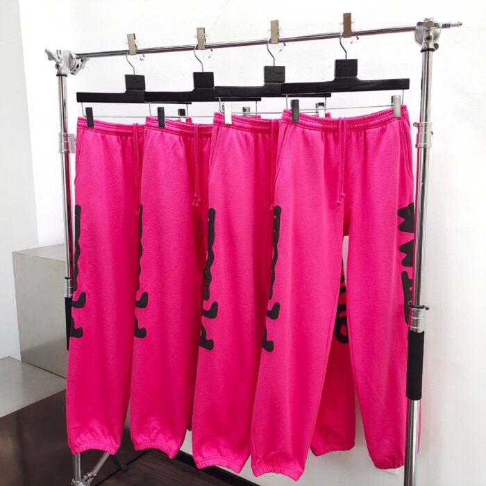 Pantaloni jogger rosa con grafica nera, stile streetwear, su supporto moderno in vetrina moda urbana.
