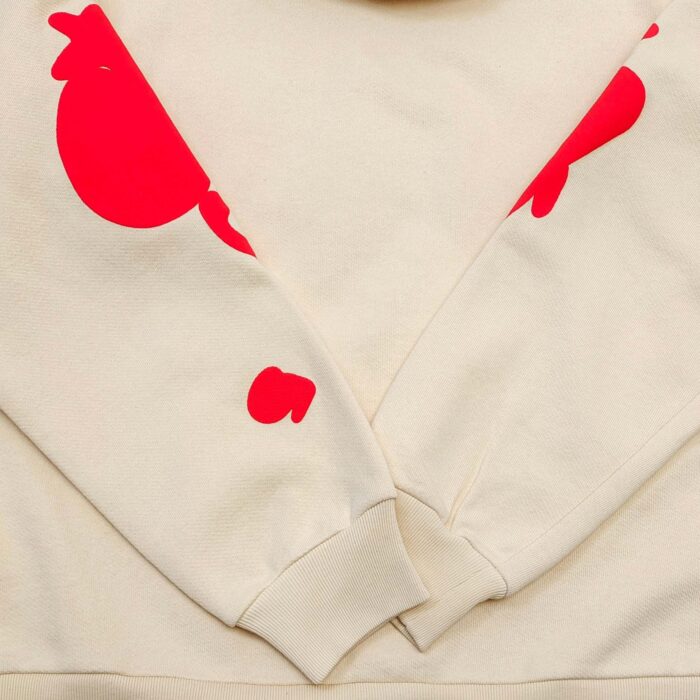 Felpa beige con grafiche di pesci astratti e dettagli rossi vivaci, stile casual e trendy.