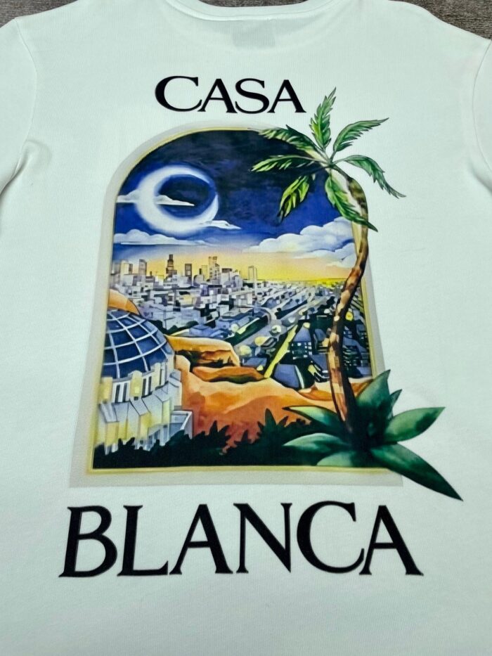 Maglietta con paesaggio notturno di Casablanca, archi, palme e skyline urbano in blu e viola.
