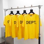 T-shirt gialli con logo nero, stile minimalista su scaffale moderno, ideale per abbigliamento casual.