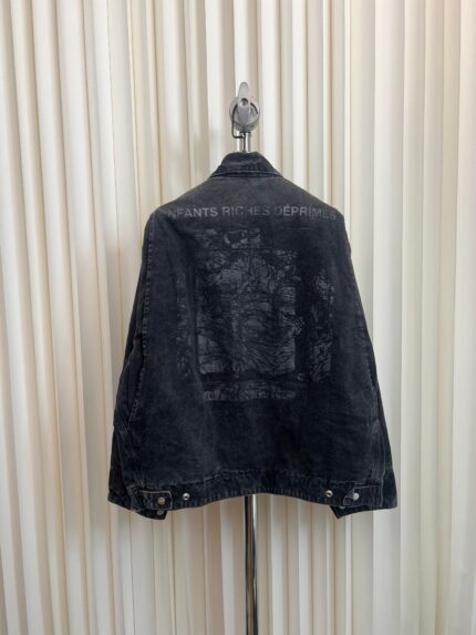 Giacca di jeans nera con grafica artistica e messaggio distintivo, stile casual e moderno.