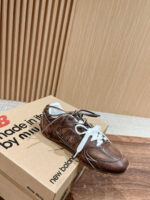 Sneaker vintage marrone New Balance su scatola in legno, stile retrò e design moderno.