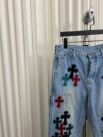 Jeans vintage chiari con ricami di croci colorate, stile casual e originale.