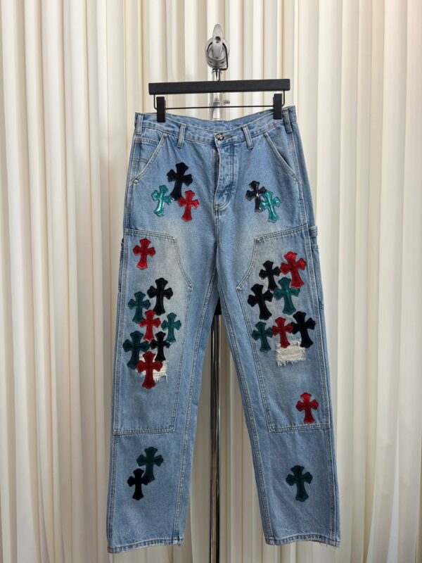 Jeans vintage denim chiaro ricamati con croci colorate e dettagli distressed, stile urbano e originale.