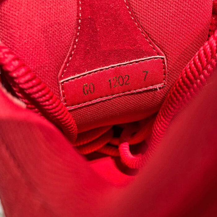 Interno di scarpa sportiva rossa vivace con dettagli moderni, logo e lacci imbottiti.