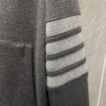 Maglione grigio in maglia a coste con tasca e dettagli a righe sportive sulla manica