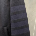 Manica di cappotto nero con strisce sovrapposte e tasca elegante, stile moderno e pratico.